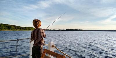 Ein Junge steht am Wasser und angelt